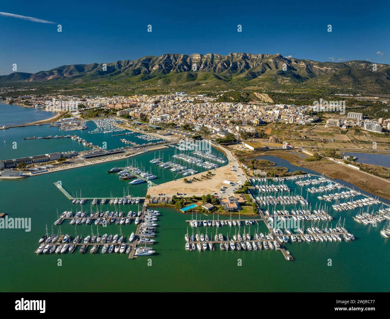 Vue aérienne de la ville de la Ràpita et de son port au premier plan. En arrière-plan, la chaîne de montagnes Montsià (Tarragone, Catalogne, Espagne) Banque D'Images