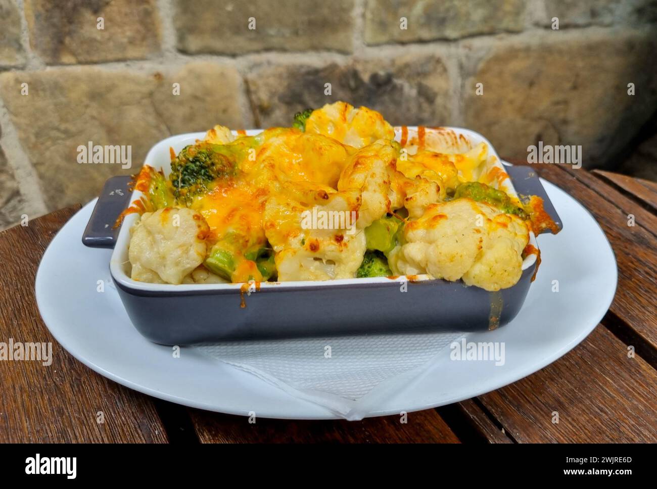 Une assiette de chou-fleur cuit au four, brocoli et fromage sur une table en bois. Banque D'Images