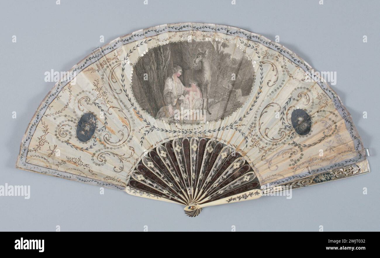 Gamme pliée, décor visage visage : dans un cartel central, une femme assise au pied d'un arbre soutient un enfant qui est allaité par une biche, un fauve est près d'eux, de chaque côté, 2 médaillons peints, à gauche, les attributs de l'amour, et à droite, des instruments de musique, et des motifs végétaux peints, un décor de gorge : le motif du vase fleuri percé d'ivoire alterne avec des fleurs stylisées, des panaches : des déchirures entourent un petit cartel peint en gris. Gal1986.270.33 manger, feuille : visage en soie, papier, feuille arrière les flèches sont recouvertes de papier, gorge bicolore, ivoire et cadre en bois, paillettes, repercussio Banque D'Images