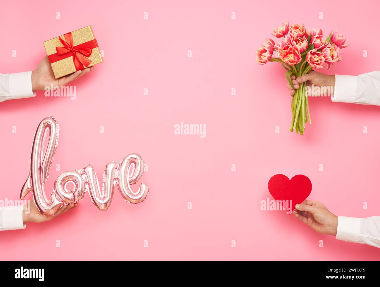 Mains d'homme avec la forme de ballon de l'amour, bouquet de tulipes, coeur de papier et boîte cadeau sur fond rose. Journée internationale de la femme, Saint-Valentin Banque D'Images