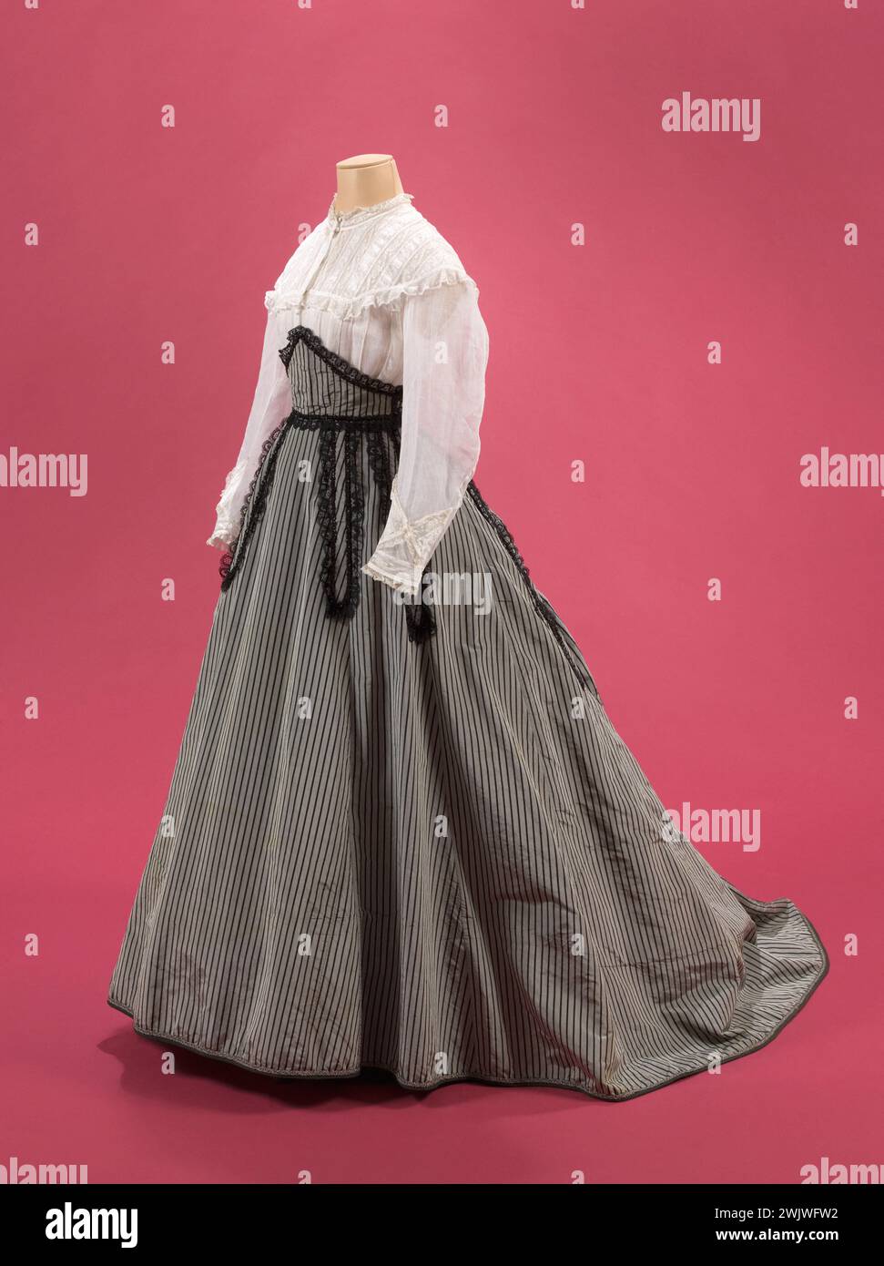 Chemisier, jupe et ceinture corselet. Blouse : organi blanc, vrai Valenciennes. Jupe et ceinture corselet : taffetas gris rayé noir, pattes doublées de dentelle Puy noire, perles noires et tubes. 1866-1868. Galliera, musée de la mode de la ville de Paris. Bandes verticales. Corsage blouse, dentelle puy noire, jupe, organi blanc, perle, second empire, taffetas gris rayon noir, valencienne Banque D'Images