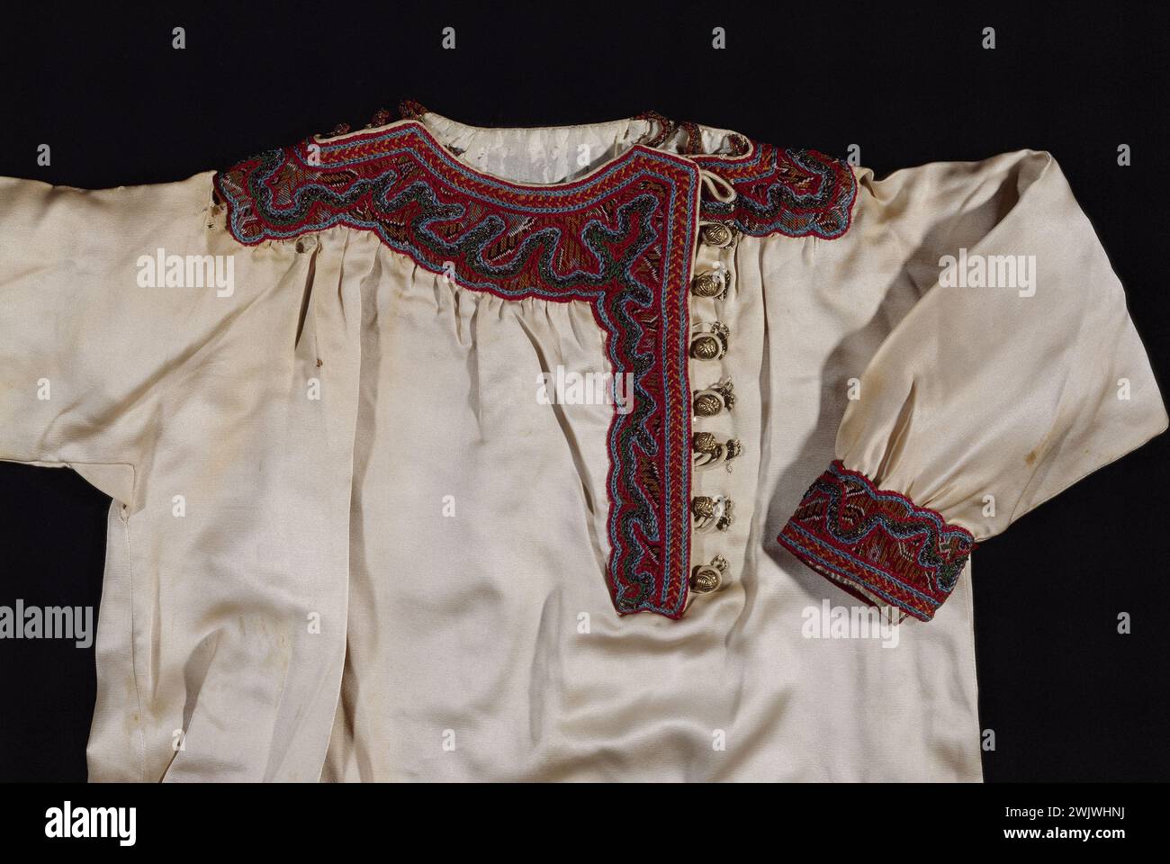 Tunique Lanvin Jeanne Garçonnet en satin de soie ivoire, broderie de laine de laine polychrome et fils de métal sur fond cachemire, boutons en métal doré, vers 1914 (vue de face posée à plat) 1914 la soie dégrace la laine Briant Remi Galliera, musée de la mode de la ville de Paris. 26124-11 FÉMININ, HAUTE-COUTURE Banque D'Images