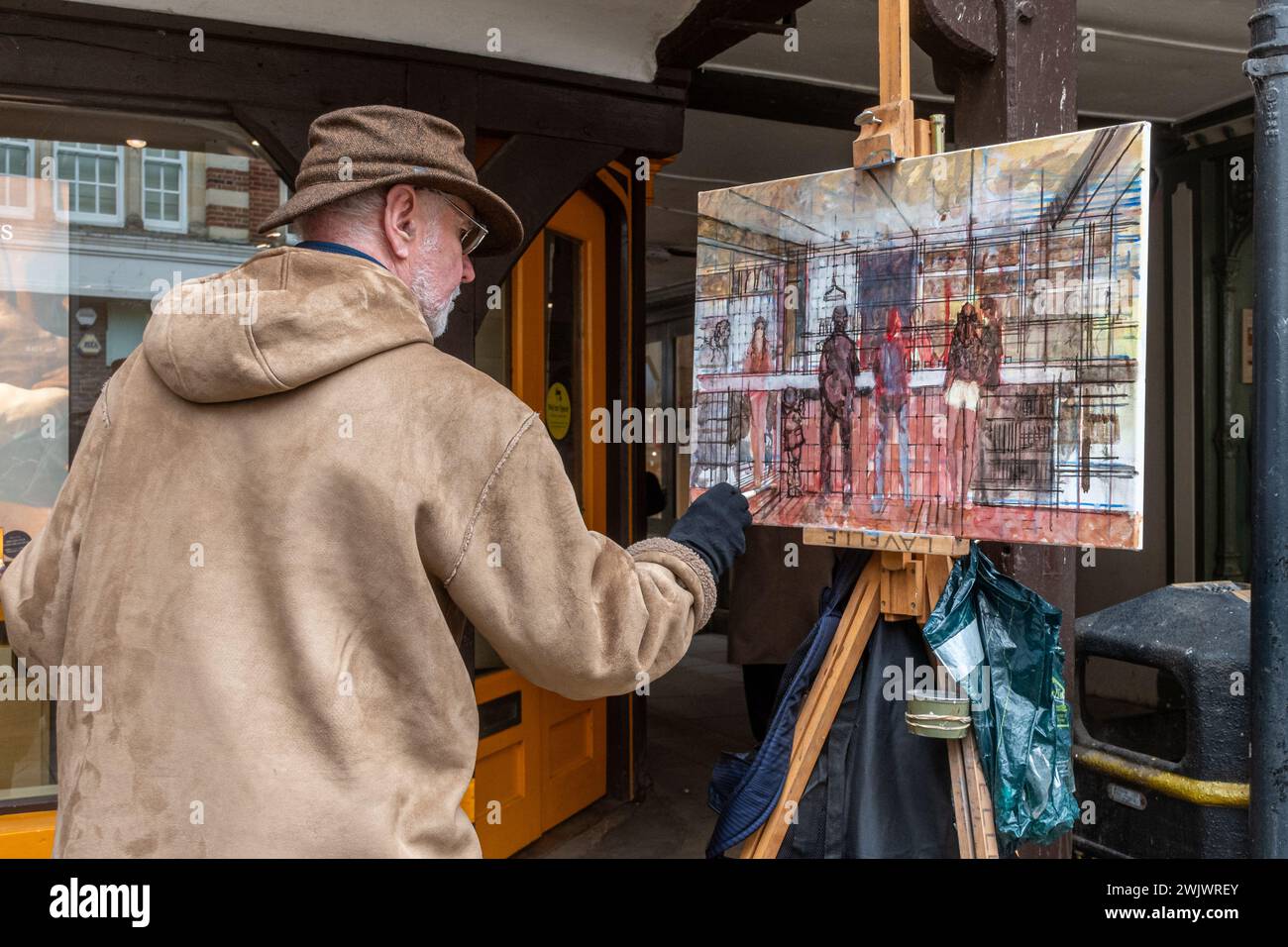 Un artiste peint une peinture de gens dans un café sur Winchester High Street, Hampshire, Angleterre, Royaume-Uni Banque D'Images