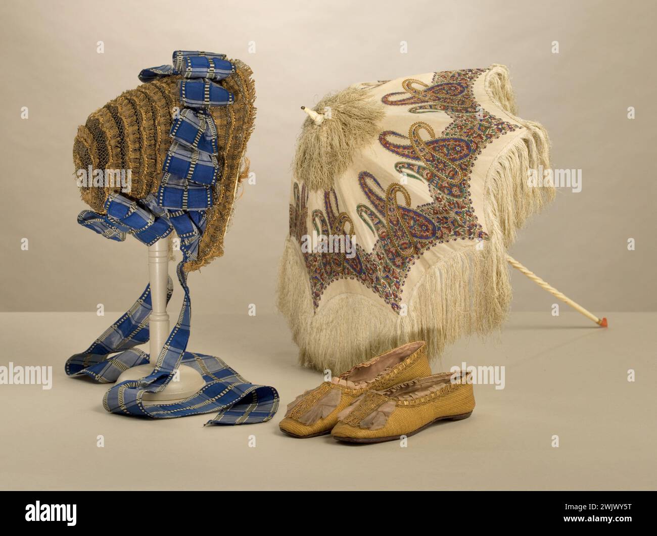 Capot, forgeron, pompes. Ombre : couverture en soie crème imprimé avec des arrangements polychromes, toile de soie crème, carcasse en métal avec huit branches, aiguille en verre rose et blanche, coulant en or ciselé, pointe, mât et poignée en ivoire torsadée, perles de corail. Capote : comme décoré de dentelle de paille disposée en spirale ; ruban écossais. Escarpins : paille blonde, noeud et doublure en taffetas de soie rose pâle, semelle en cuir. 1848-1860. Galliera, musée de la mode de la ville de Paris. Impression polychrome cachemire accessoire, aiguille, bague, blanc, capuche, cordon, tuile bleue, chaussure, flux, couverture, disposition polychrome, doublure, t Banque D'Images