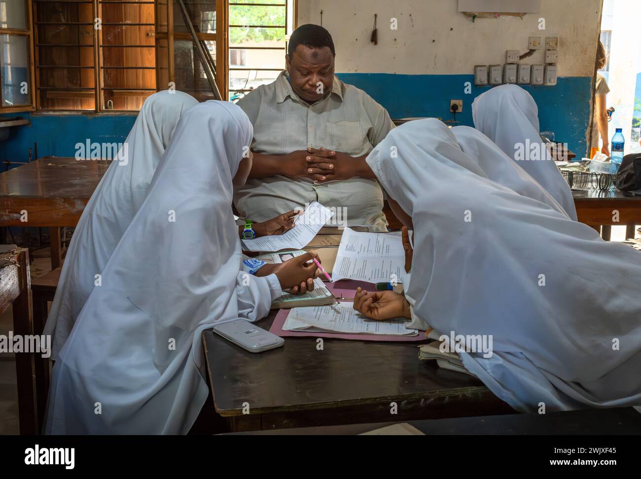 Des filles musulmanes travaillent avec leur professeur dans une leçon de mathématiques à l'école secondaire Jambiani à Jambiani, Zanzibar, Tanzanie. Banque D'Images