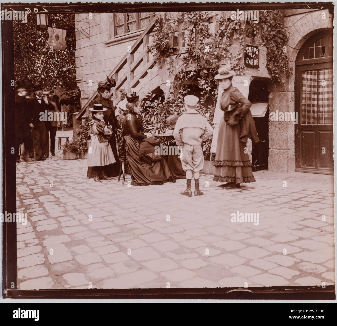 Exposition universelle de 1900. Vieux Paris. 'Femmes et enfants autour d'une table devant l'auberge de la garde dans le Vieux Paris, Paris'. Photo club de Paris. ARISTOTYPE. Paris, musée Carnavalet. 100476-4 année 1900, exposition universelle Banque D'Images