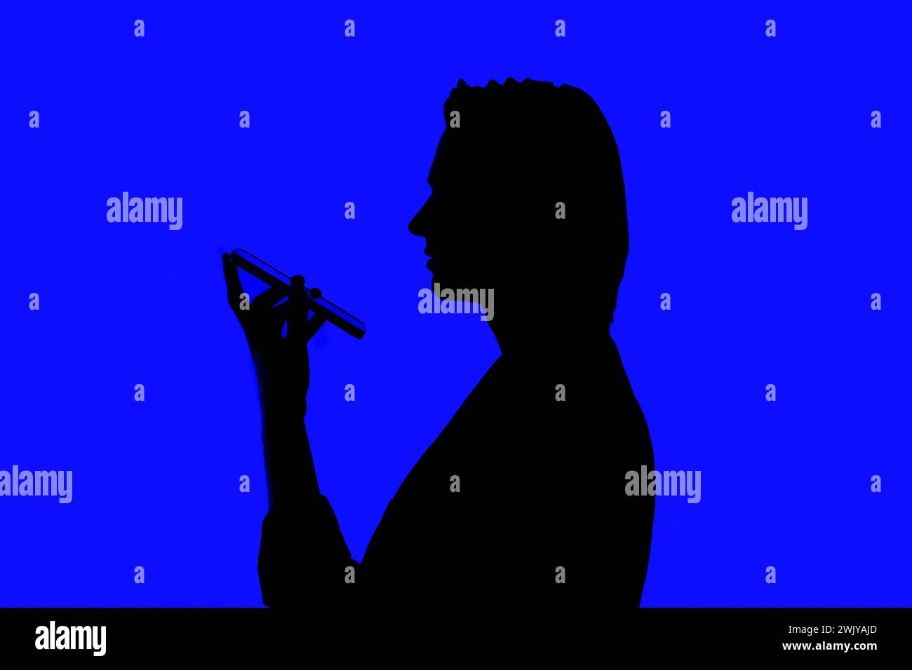 Silhouette un homme d'affaires élégant parlant sur un téléphone portable dans une veste debout sur un fond bleu brillant, concepts futuristes d'IA Banque D'Images