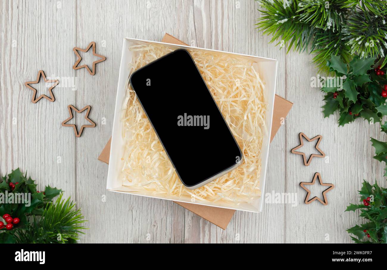 Cadeau tendance pour smartphone. Cadeau de Noël et maquette de smartphone sur fond en bois. Plat, vue de dessus. Concept de shopping de la vente du vendredi fou Banque D'Images