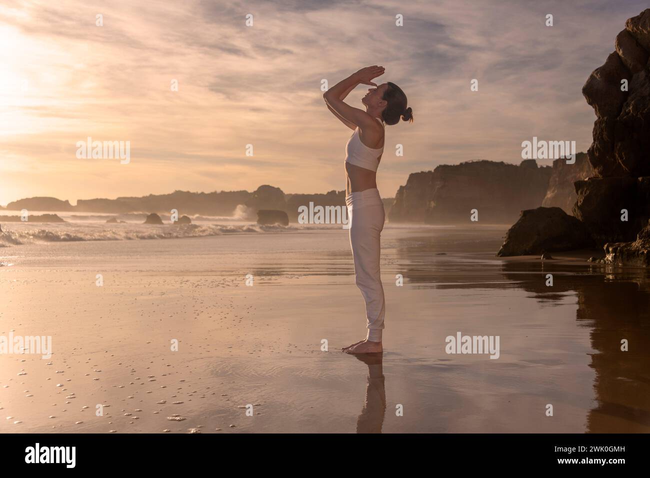 femme debout sur une plage méditant au lever du soleil, au coucher du soleil Banque D'Images femme debout sur une plage méditant au lever du soleil, au coucher du soleil Banque D'Images