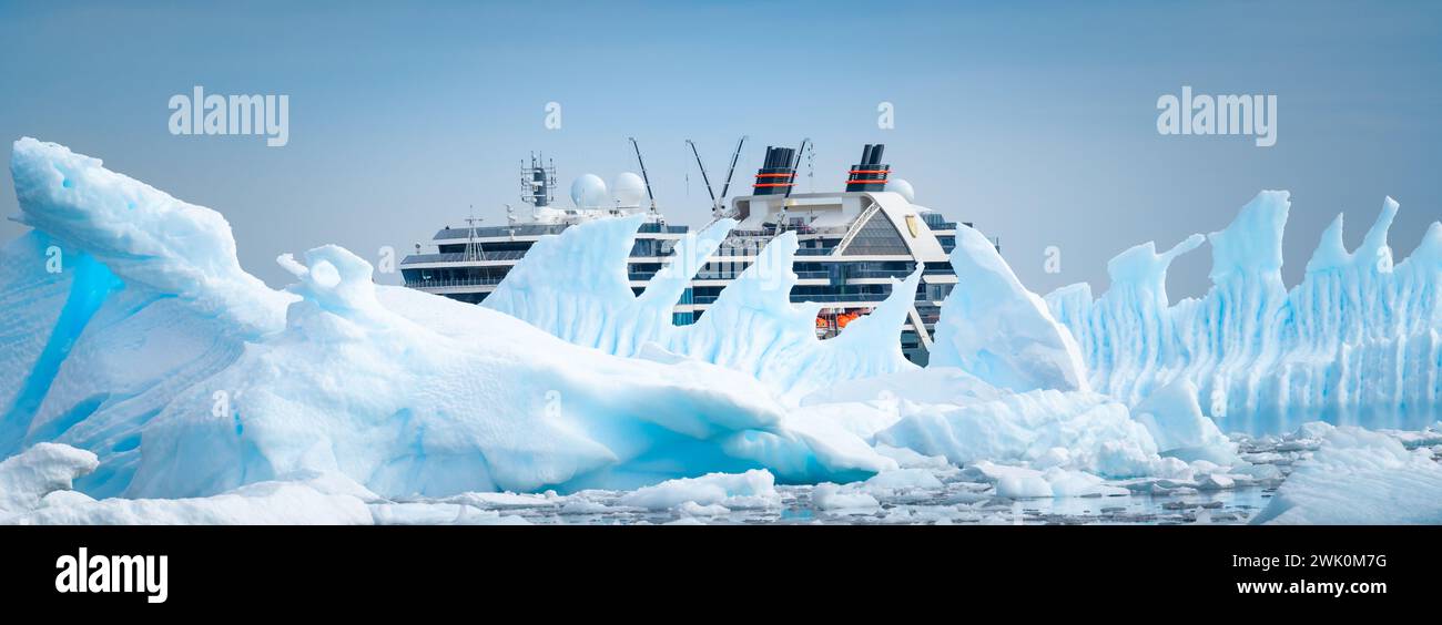Fish Islands, Antarctique - 12 janvier 2024 : bateau de croisière Seabourn Pursuit caché derrière un bel iceberg en Antarctique. Banque D'Images