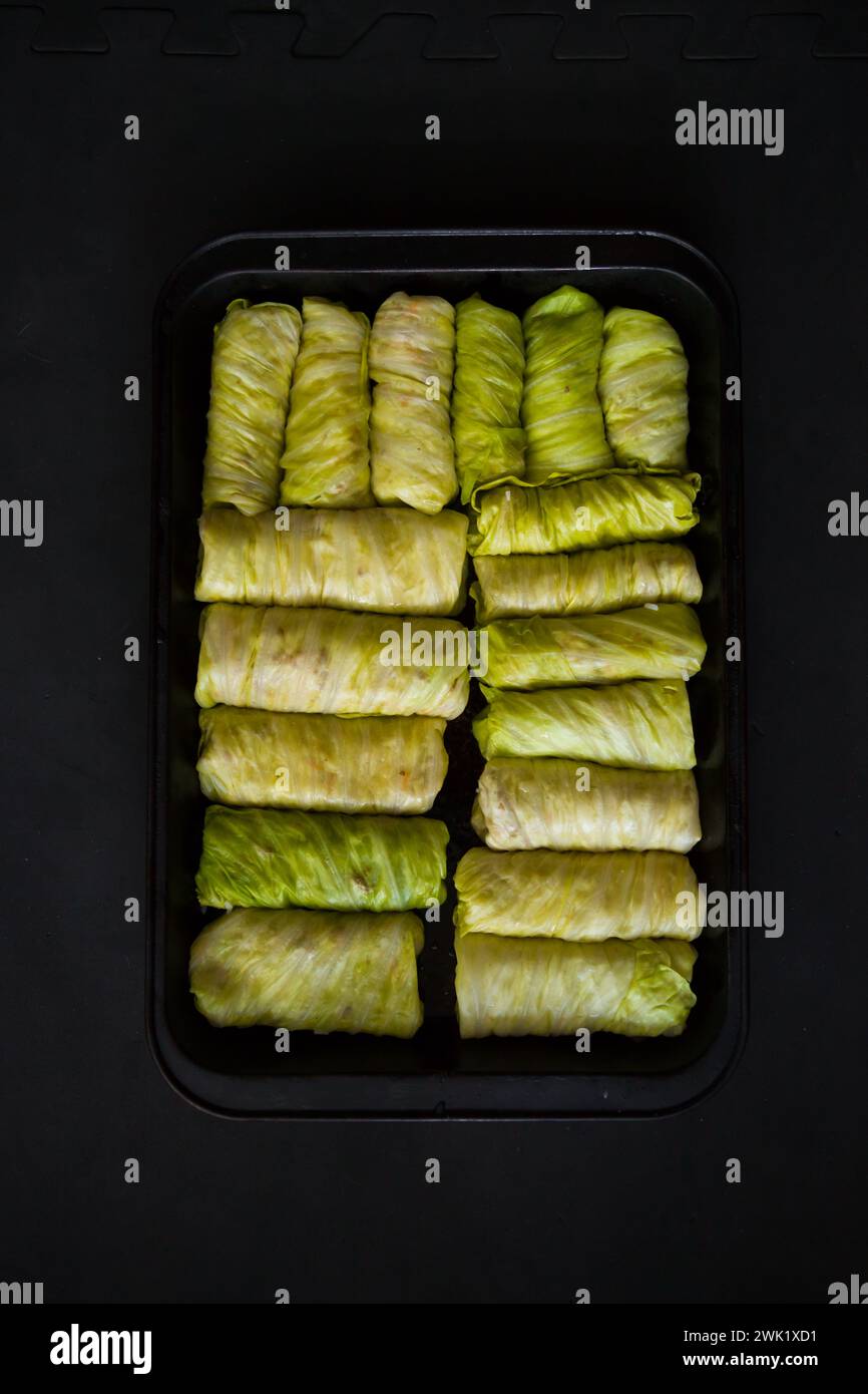 Rouleaux de chou farcis dans une plaque de cuisson sur un fond noir. Mise au point sélective. Tonique. Plat traditionnel ukrainien. Cuisine d'Europe de l'est. vue de dessus, Banque D'Images