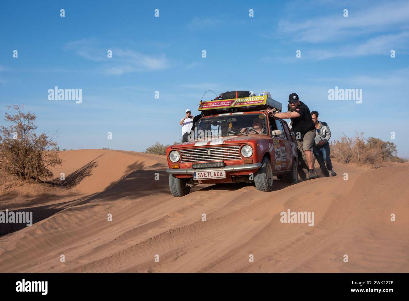 D'autres équipes poussent le véhicule belge Svetlada Team du sable profond près de Erg Chigaga, au Maroc. Le rallye amateur Budapest-Bamako a célébré la 15ème course. Il a commencé le 30 janvier de Fès, Maroc et se terminera le 12 février à Freetown, Sierra Leone. Le parcours original a été réorganisé pour des raisons évidentes de sécurité, tout comme dans la course Paris-Dakar, mais en même temps la distance a été étendue. Au fil des ans, le rallye amateur Budapest-Bamako est devenu l’une des courses les plus longues et les plus exigeantes au monde. (Photo Krisztian Elek/SOPA images/SIPA USA) Banque D'Images