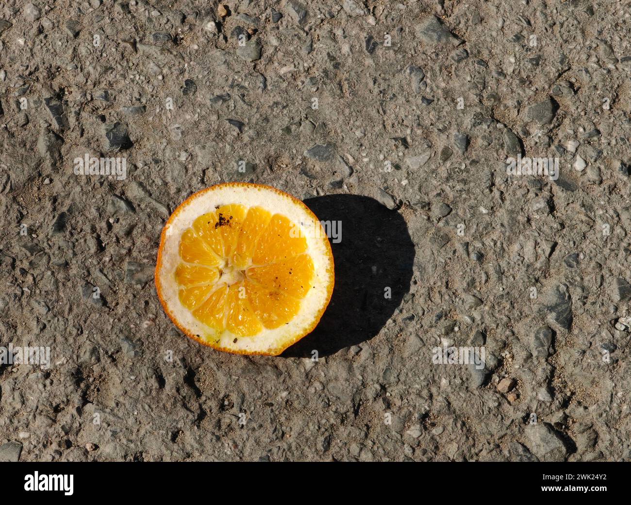 Tranquillité acidulée. Un demi-fruit orange au milieu de la solitude urbaine. Banque D'Images