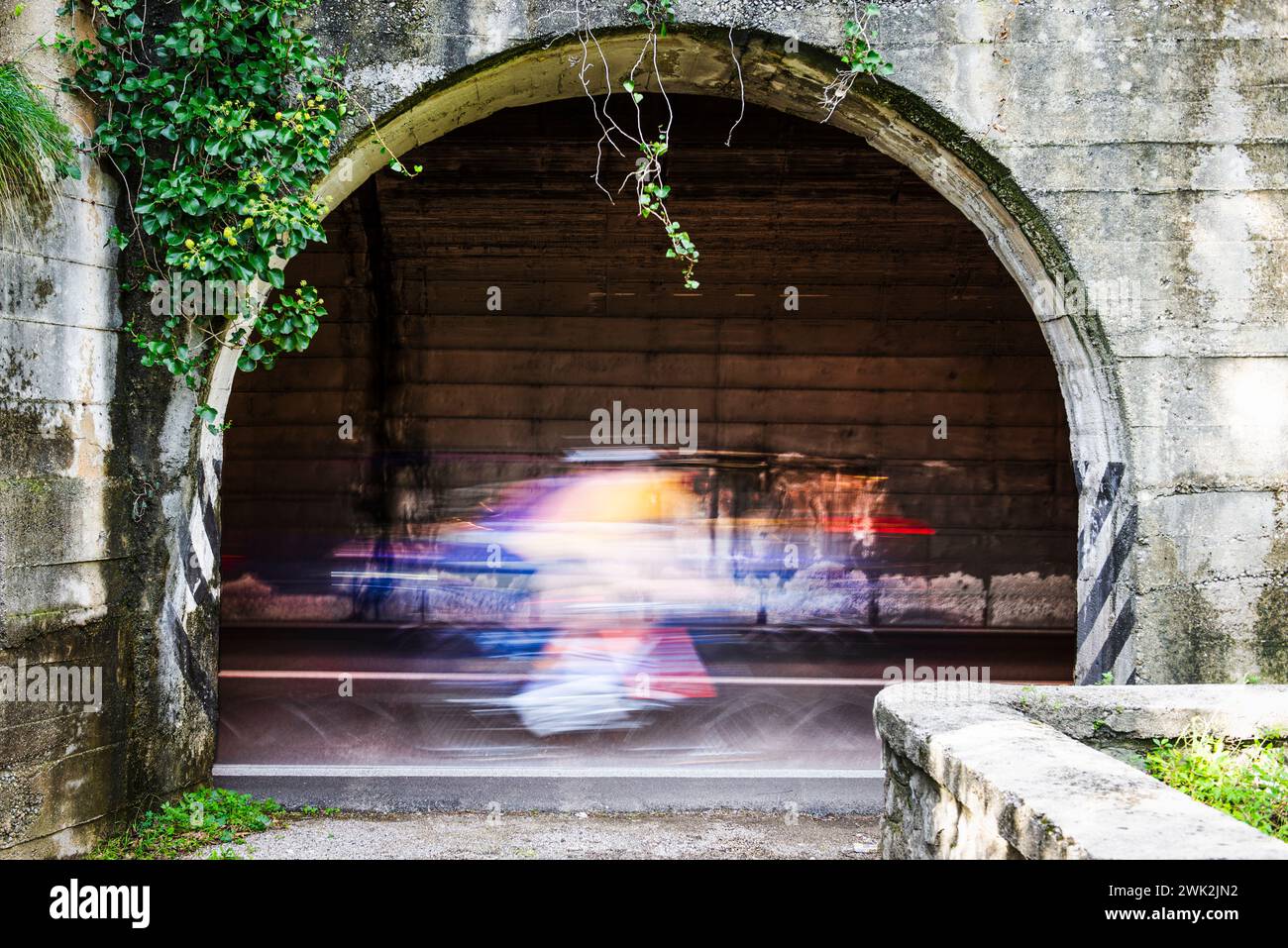 Cyclistes et voitures avec flou de mouvement dans un tunnel de la route panoramique Gardesana occidentale au-dessus de Limone, Lombardie, Italie Banque D'Images