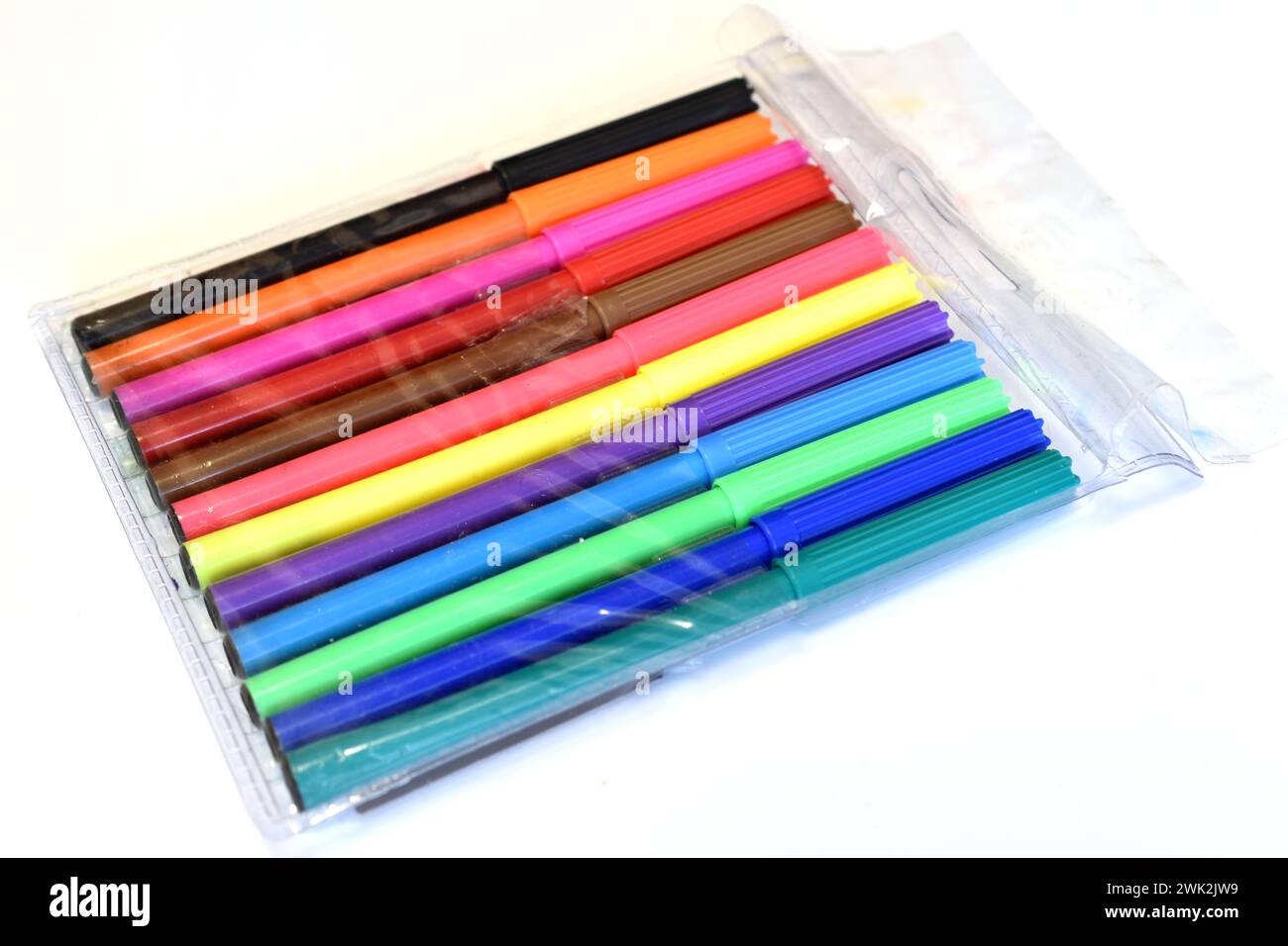 Les marqueurs de différentes couleurs dans un emballage transparent reposent sur un fond blanc. Banque D'Images