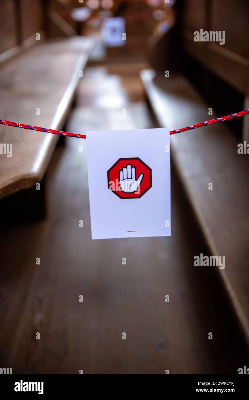 Un signe blanc accroché à une ficelle avec le symbole d'une main sur un hexagone rouge. Le panneau est destiné à indiquer que les bancs derrière lui ne peuvent pas être utilisés. Banque D'Images