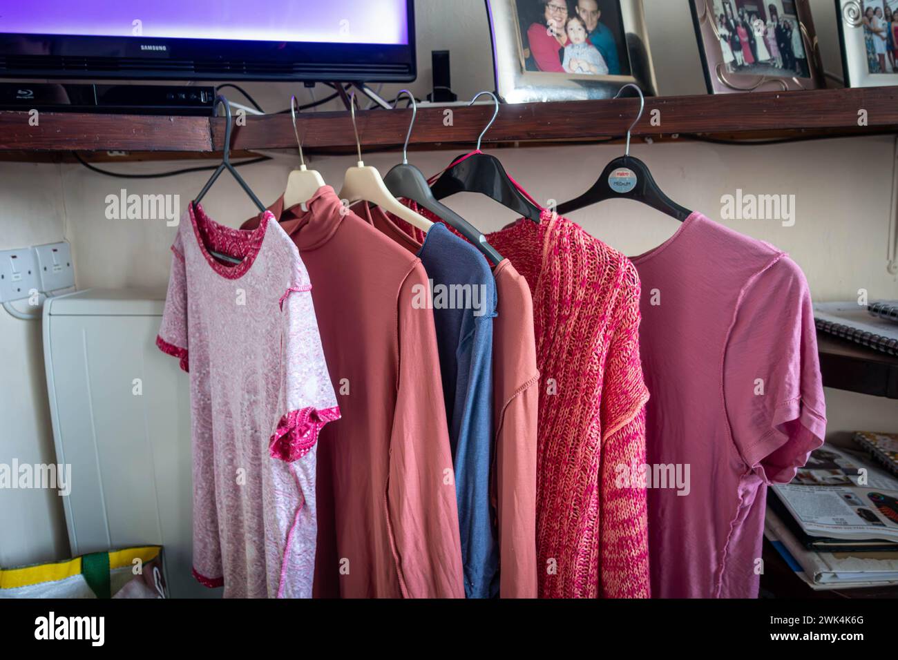 Des vêtements propres et en fer accrochent sur des cintres à vêtements à partir d'une étagère inb un salon Banque D'Images
