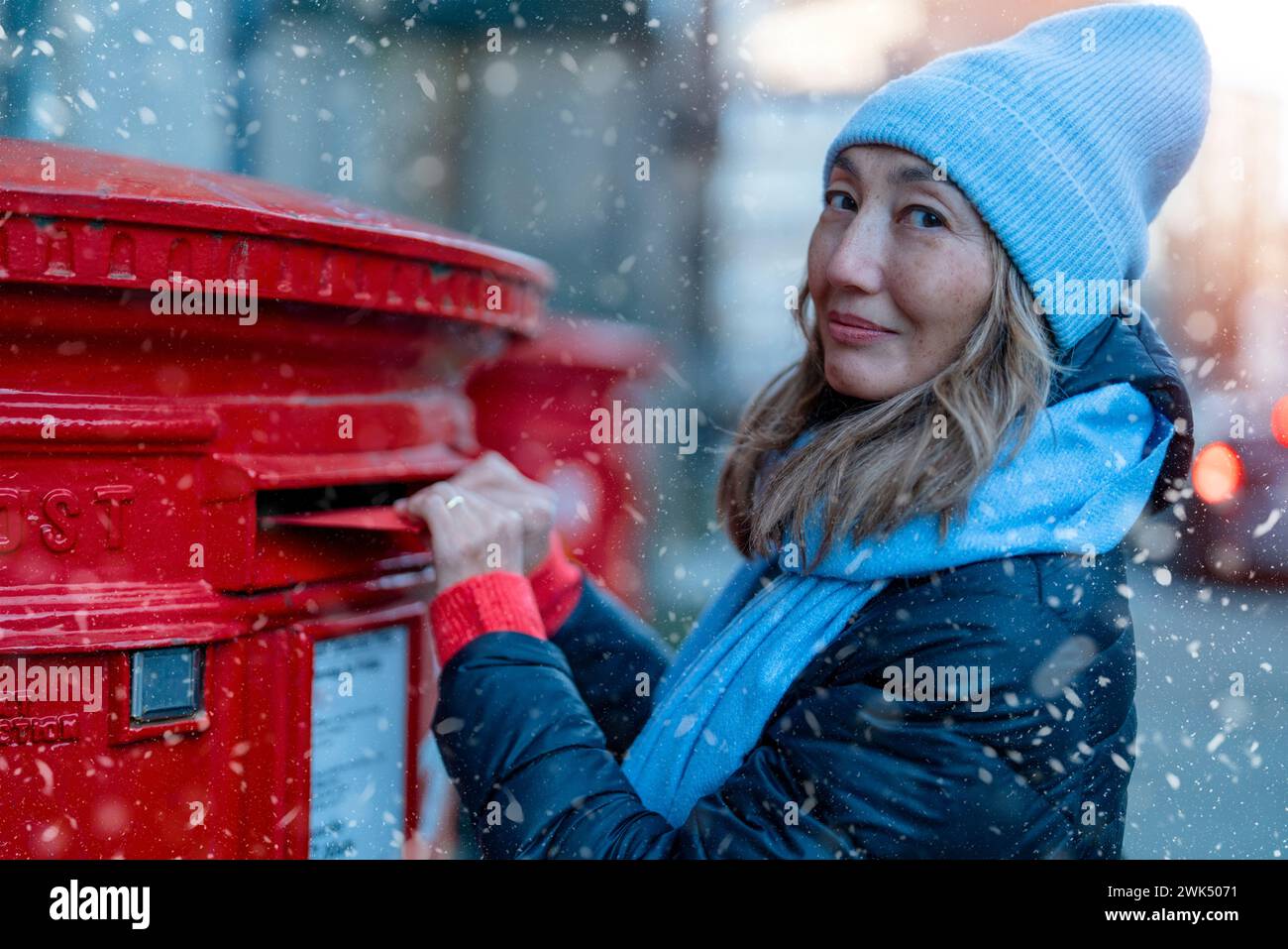 femme mettant une carte à la boîte postale rouge et marchant autour Ville anglaise Banque D'Images