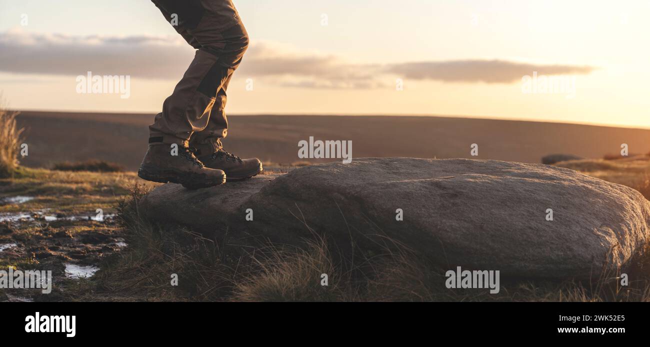 Homme dans des bottes spéciales marchant dans les montagnes atteignant la destination et sur le sommet de la montagne dans Peak District au coucher du soleil le jour d'automne voyage vie Banque D'Images