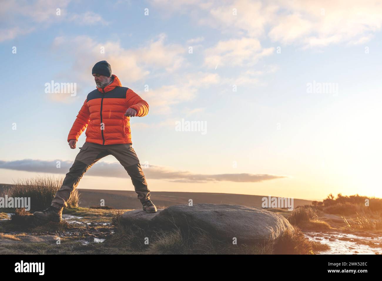 Homme dans des bottes spéciales marchant dans les montagnes atteignant la destination et sur le sommet de la montagne dans Peak District au coucher du soleil le jour d'automne voyage vie Banque D'Images
