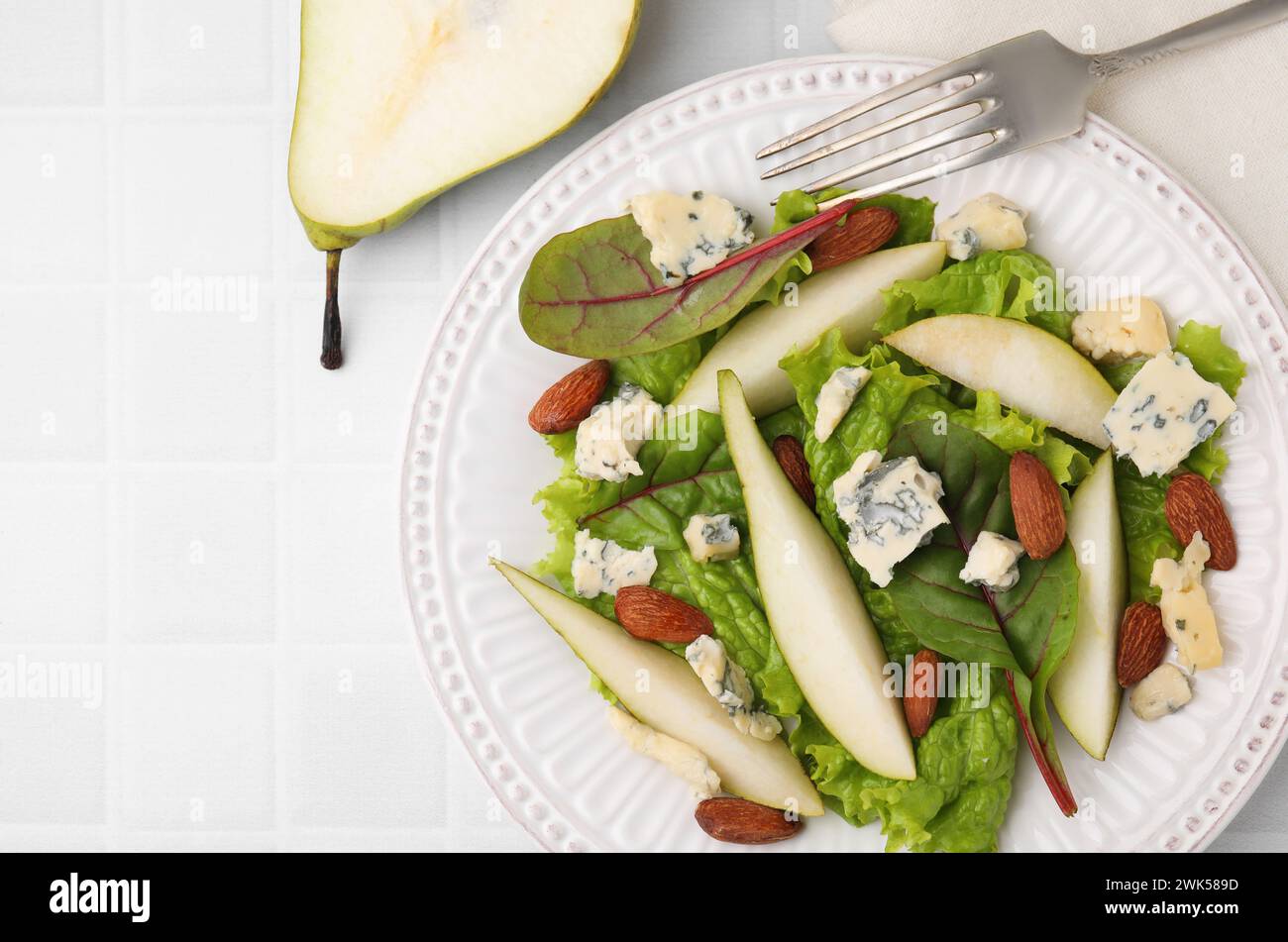 Délicieuse salade de poires et fruits sur table carrelée blanche, vue de dessus. Espace pour le texte Banque D'Images