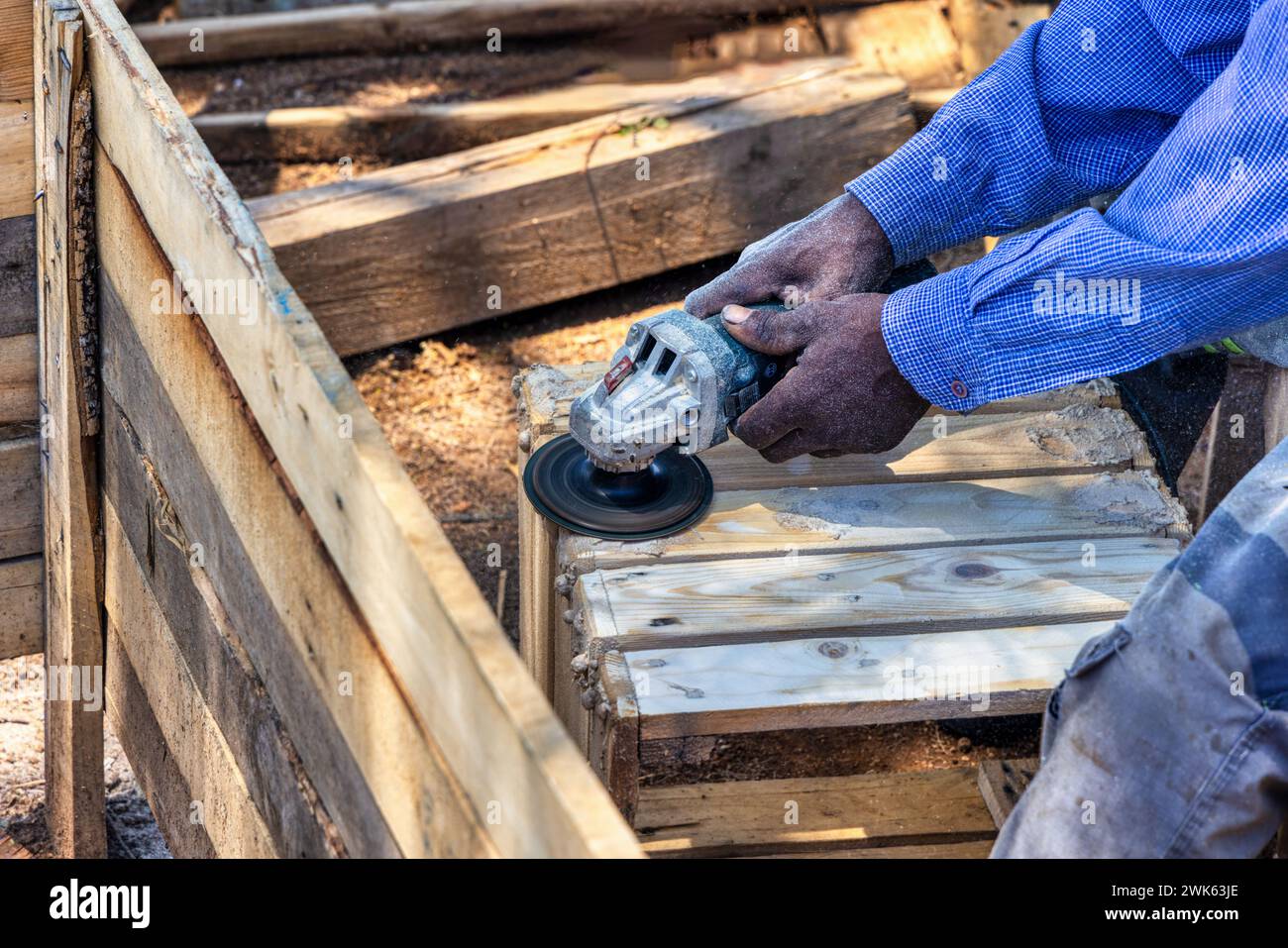 charpentier afro-américain faisant une maison wendy, hangar en bois à l'extérieur, gros plan, il meule les planches et les assemble en panneaux Banque D'Images