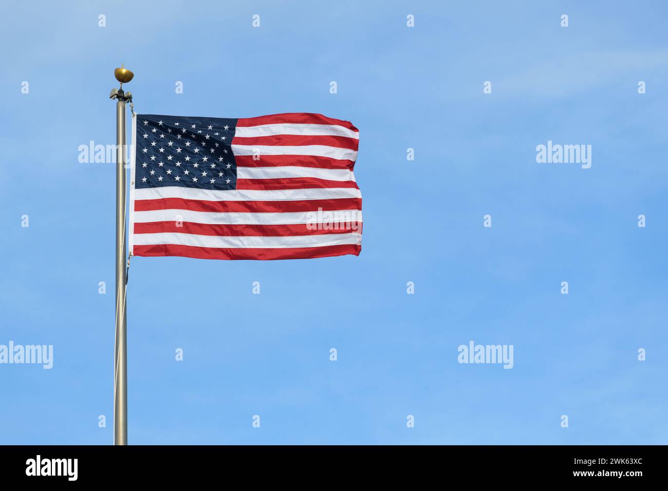 Drapeau des étoiles et des rayures des États-Unis tendu dans le vent contre le ciel bleu Banque D'Images