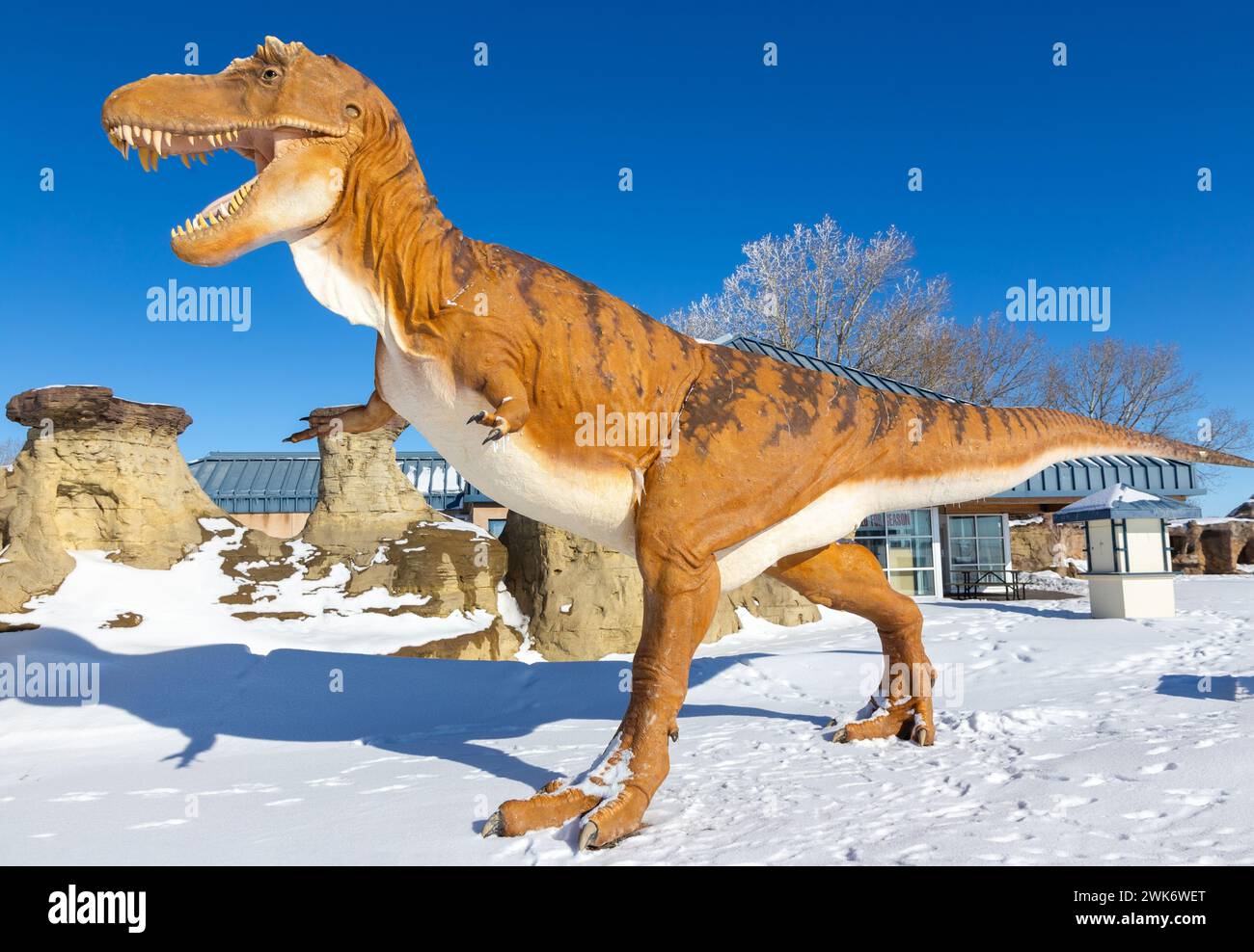 Massive Dinosaur animal figure modèle Statue Walking by Hoodoo Rock formations. Centre d'accueil touristique des parcs de l'Alberta du Sud à Milk River, Canada Banque D'Images