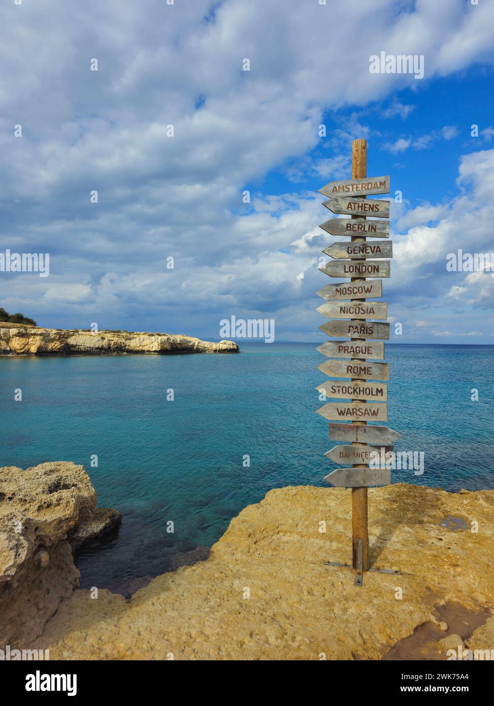 Panneau de direction des capitales européennes sur une planche de bois dans la côte contre ciel nuageux Banque D'Images