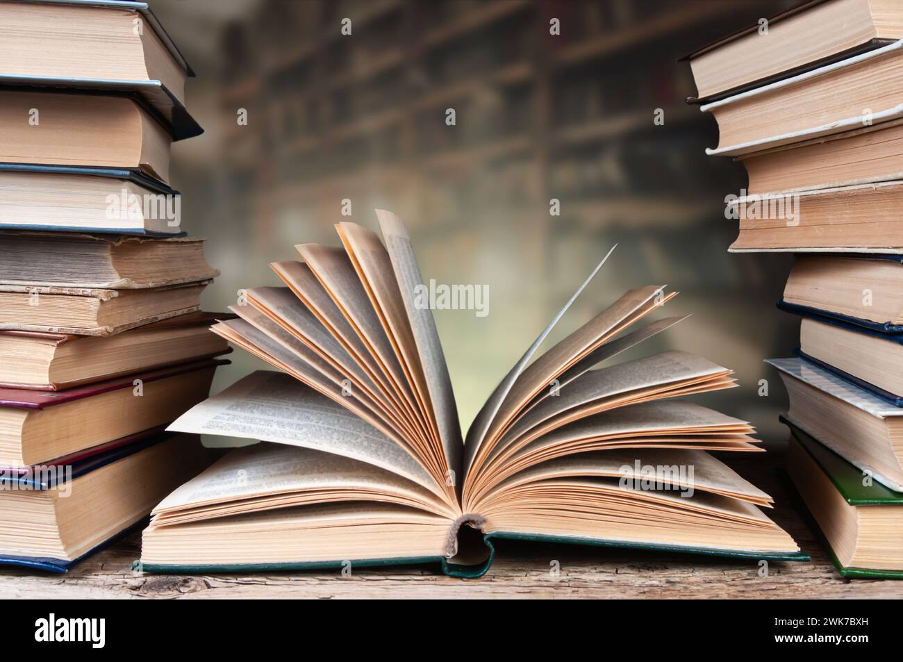 Une pile de vieux livres sur une surface en bois sur un fond d'étagères Banque D'Images