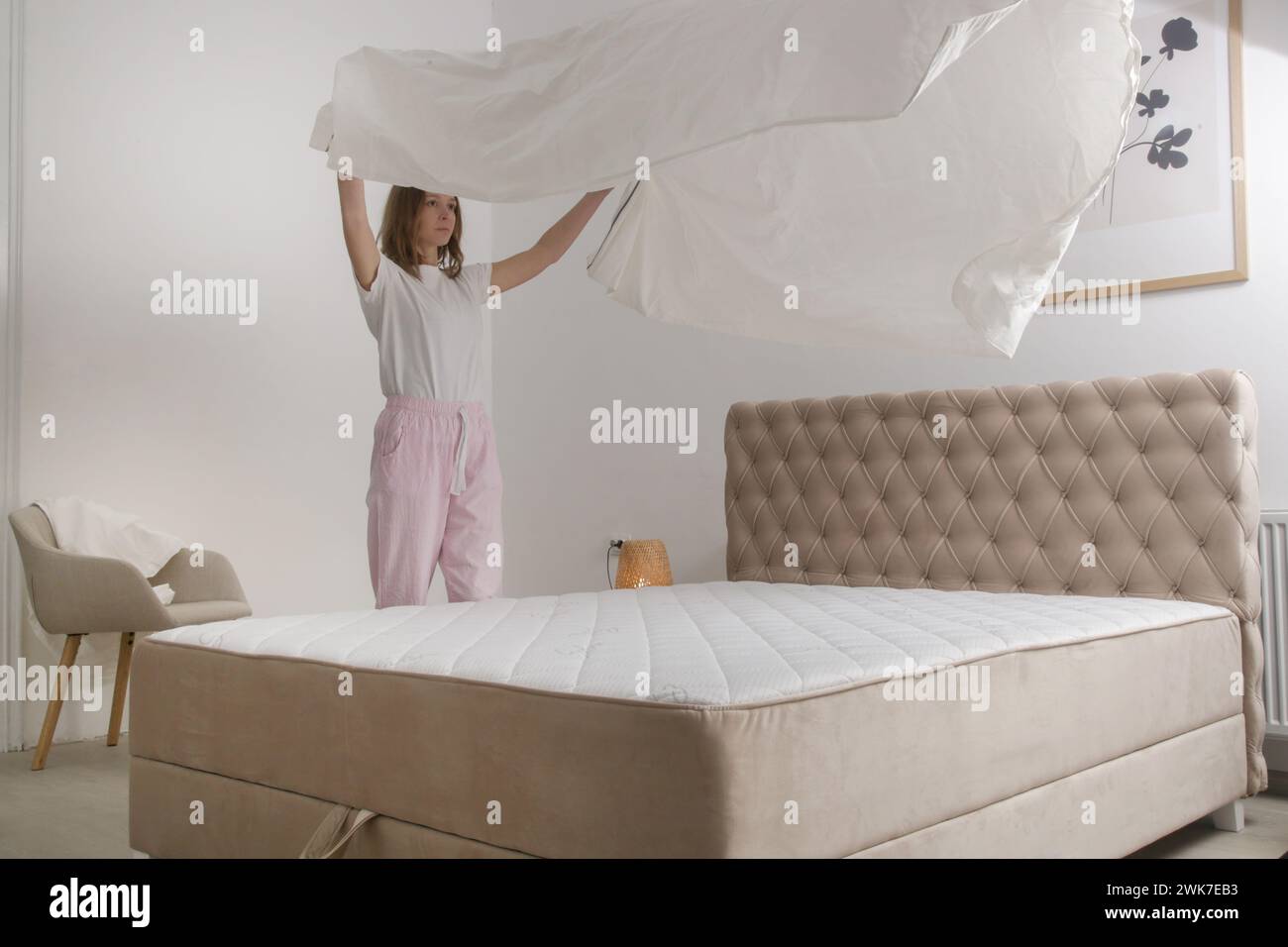 Femme changeant le linge de lit à la maison dans sa chambre à coucher, style de vie domestique confortable, ménage de femme au foyer, rangement de la chambre, concept de ménage. Banque D'Images