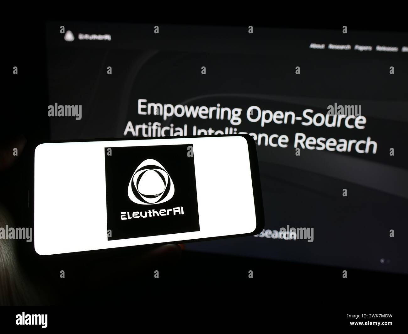 Personne tenant le téléphone portable avec le logo du groupe de recherche en intelligence artificielle EleutherAI devant la page Web. Concentrez-vous sur l'affichage du téléphone. Banque D'Images