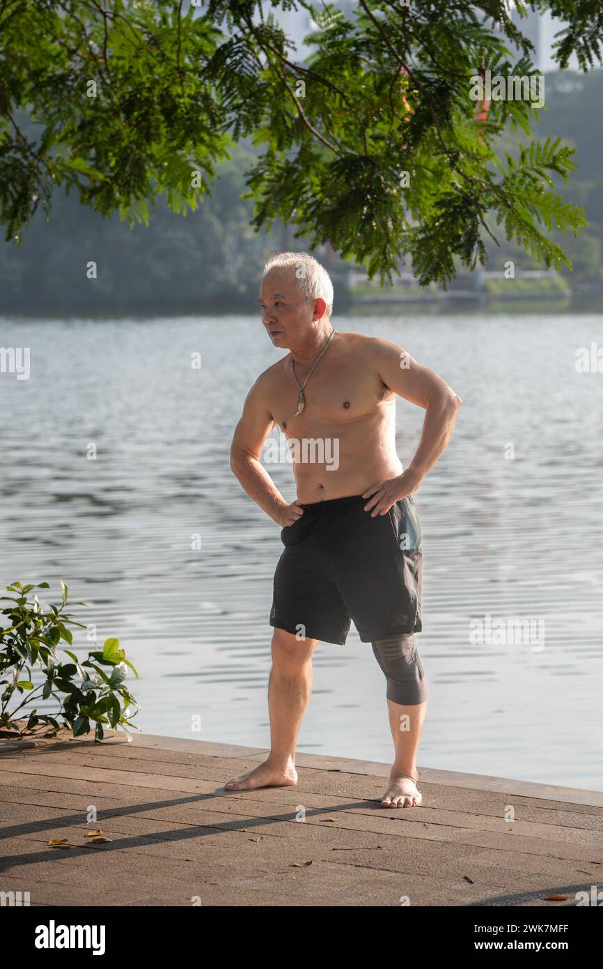 Homme faisant des exercices tôt le matin autour du lac Hoan Kiem à Hanoi, Vietnam Banque D'Images