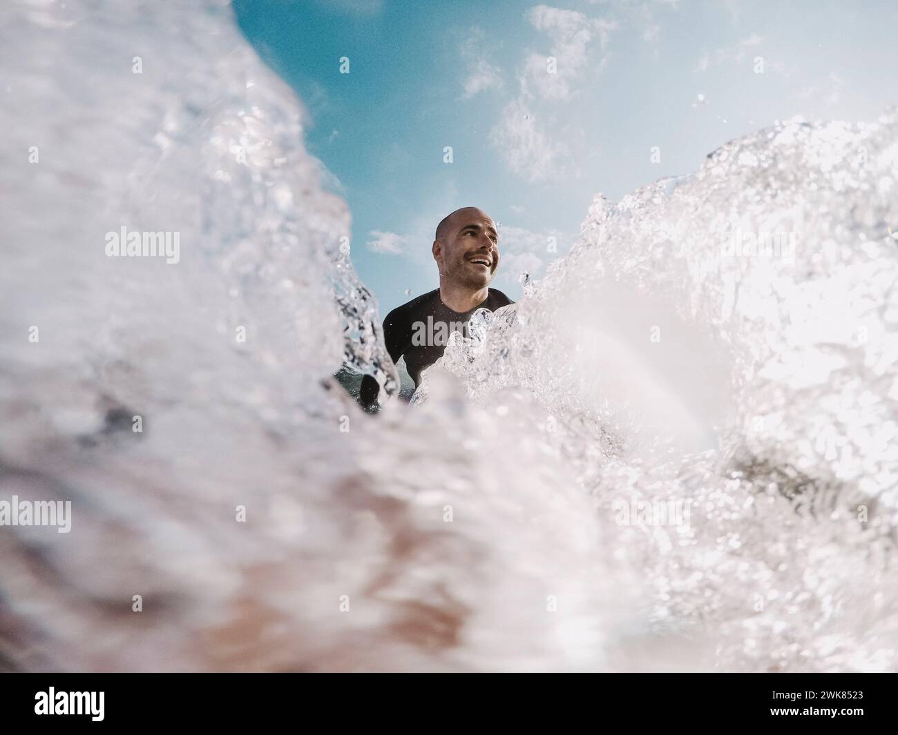 Surfeur pagayant sur une planche de surf parmi les éclaboussures d'eau, Tenerife, îles Canaries, Espagne Banque D'Images