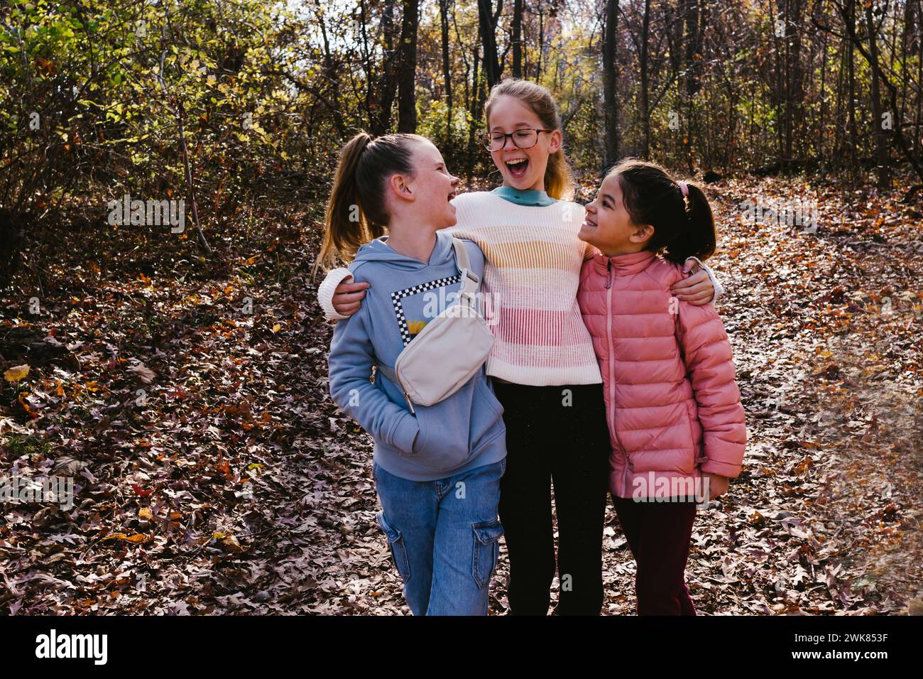 Les filles rient et parlent de multi race dans les feuilles d'automne dans la forêt Banque D'Images