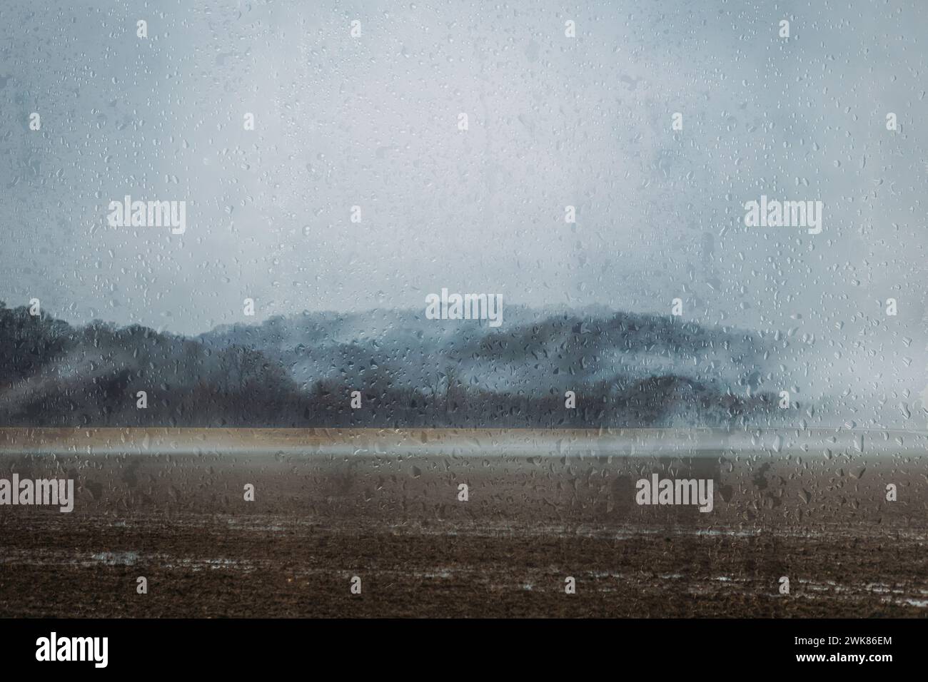 Paysage sombre à travers les gouttes de pluie sur la fenêtre le jour de pluie Banque D'Images