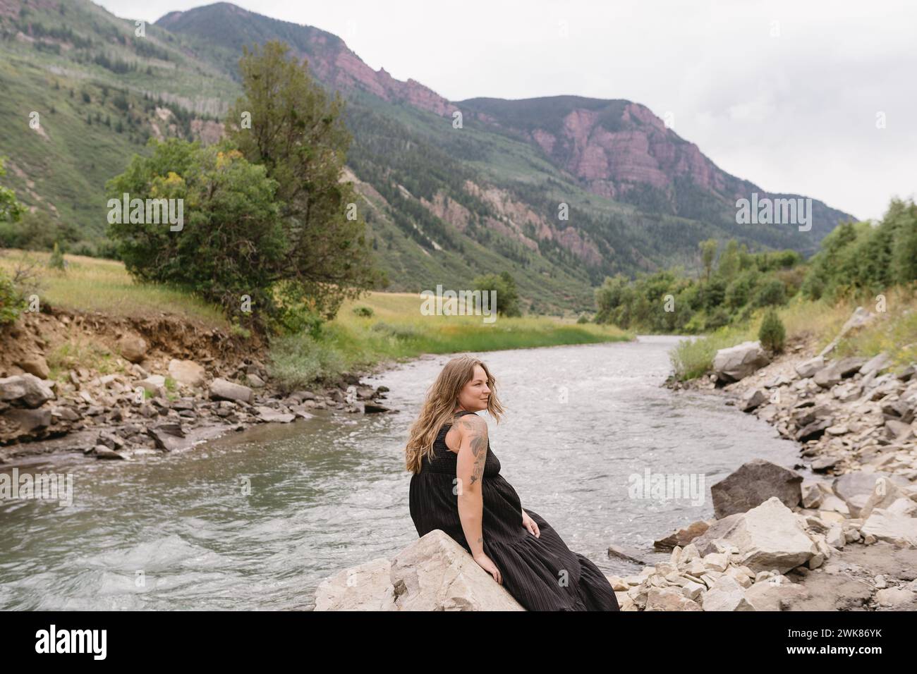 Femme assise sur un rocher près du fleuve Colorado et des montagnes Banque D'Images