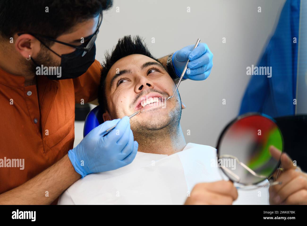 Un patient partage un moment joyeux avec son dentiste lors d’un examen, mettant en valeur un environnement de soins dentaires confortable et convivial Banque D'Images