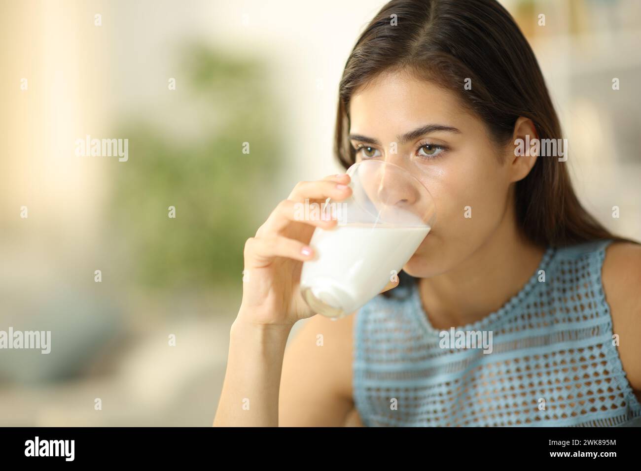 Femme sérieuse buvant du lait de verre transparent à la maison Banque D'Images
