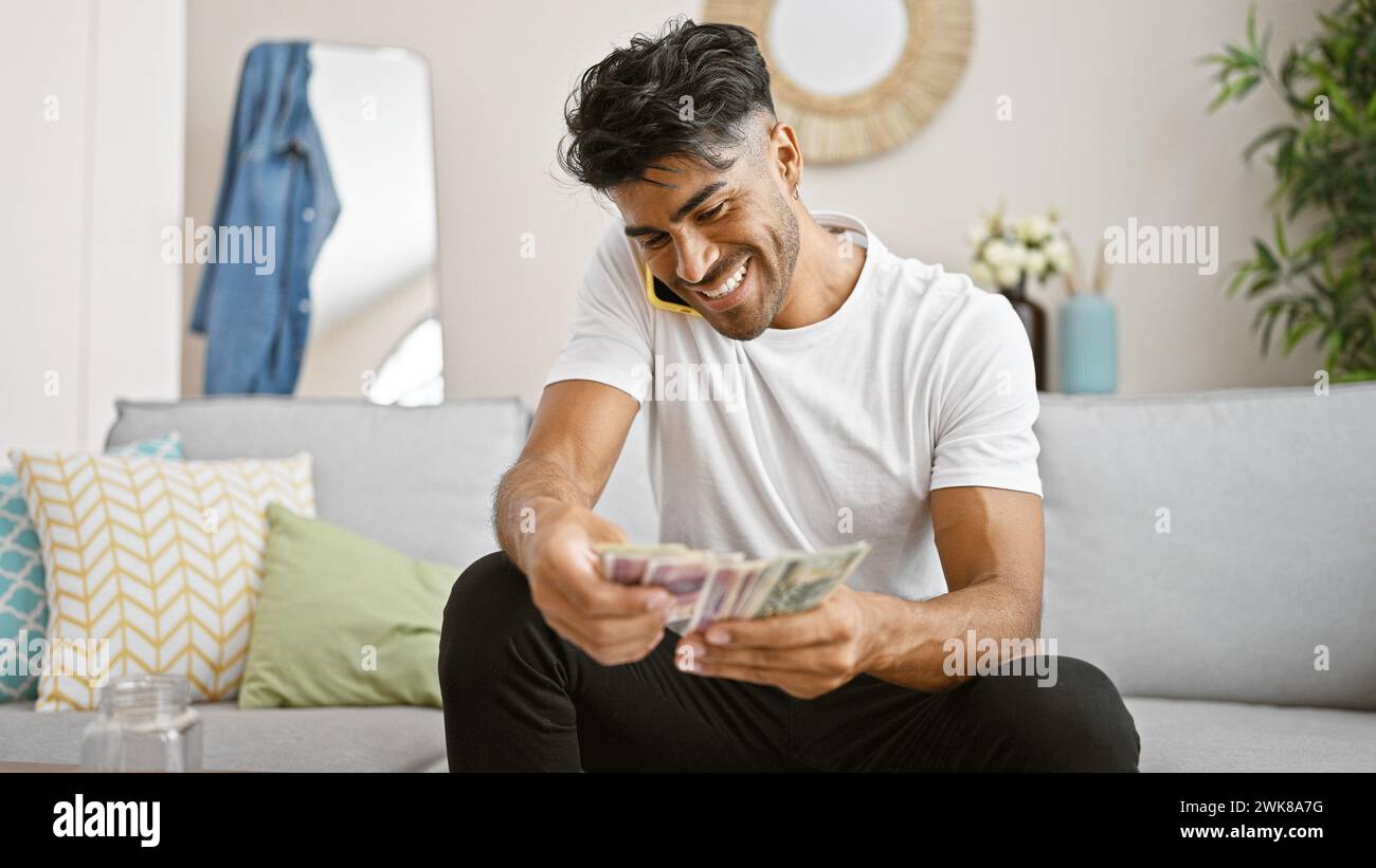 Un jeune homme hispanique joyeux compte du zloty polonais à la maison. Banque D'Images