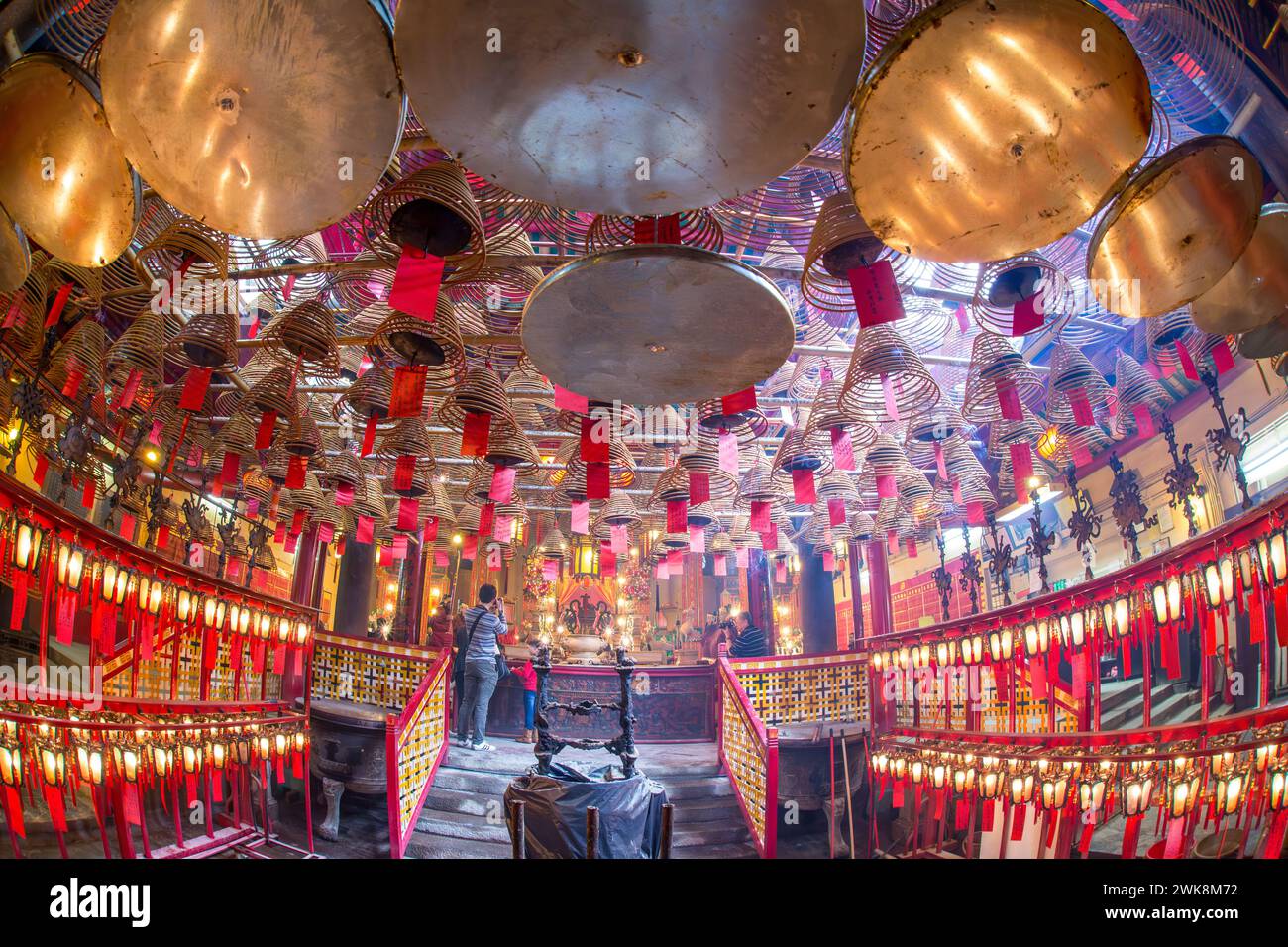 Les bobines d'encens brûlantes envoient des prières au paradis dans le temple Man Mo, un temple bouddhiste à Hong Kong, en Chine. Les photographes prennent des photos de l'autel. Banque D'Images