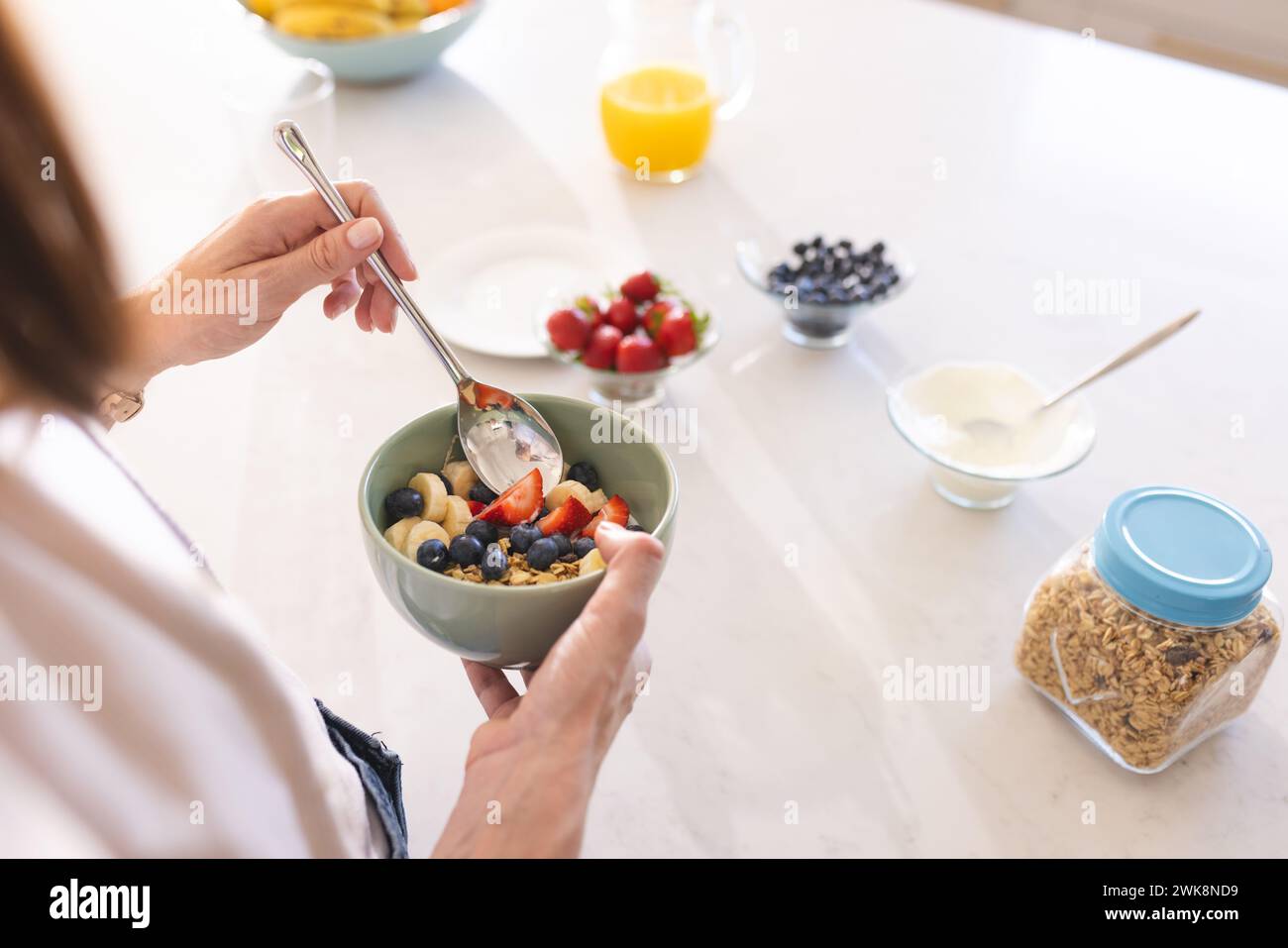 Une personne prépare un bol de petit déjeuner sain avec des fruits frais et du yaourt Banque D'Images
