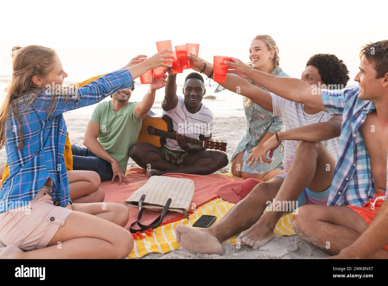 Divers amis toast sur une plage au coucher du soleil, ayant une fête, avec un espace de copie Banque D'Images