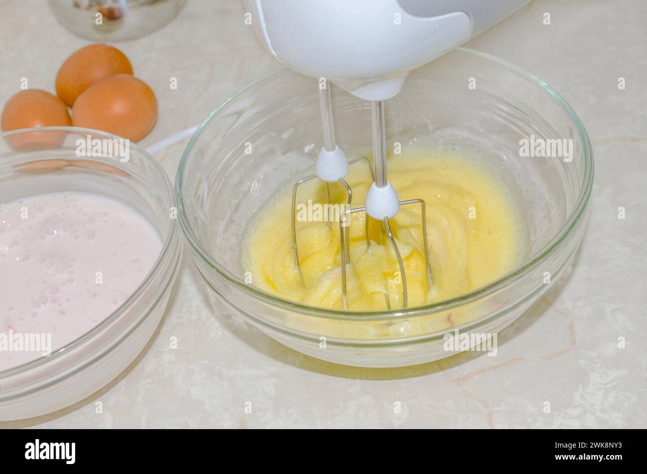 Les jaunes d'œufs sont fouettés avec du sucre dans le bol du batteur Banque D'Images