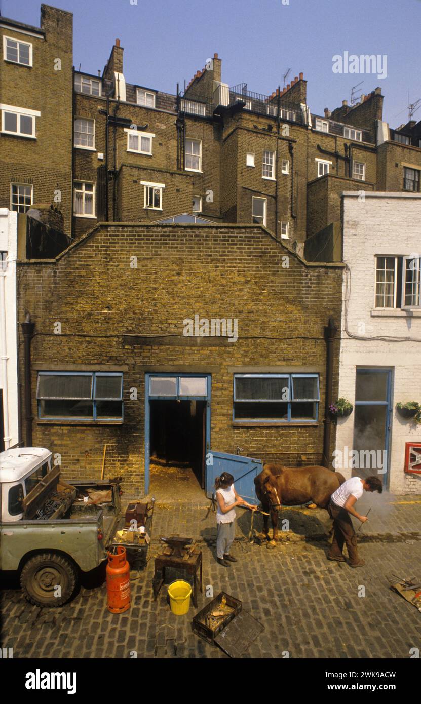 Écuries de chevaux Londres 1980s. Ross Nye stables maintenant connu sous le nom de Hyde Park stables à Bathurst Mews, Londres W2. Mobile Farrier, un forgeron noir équipé d'un nouveau fer à cheval. ANGLETERRE ROYAUME-UNI 1989 HOMER SYKES Banque D'Images