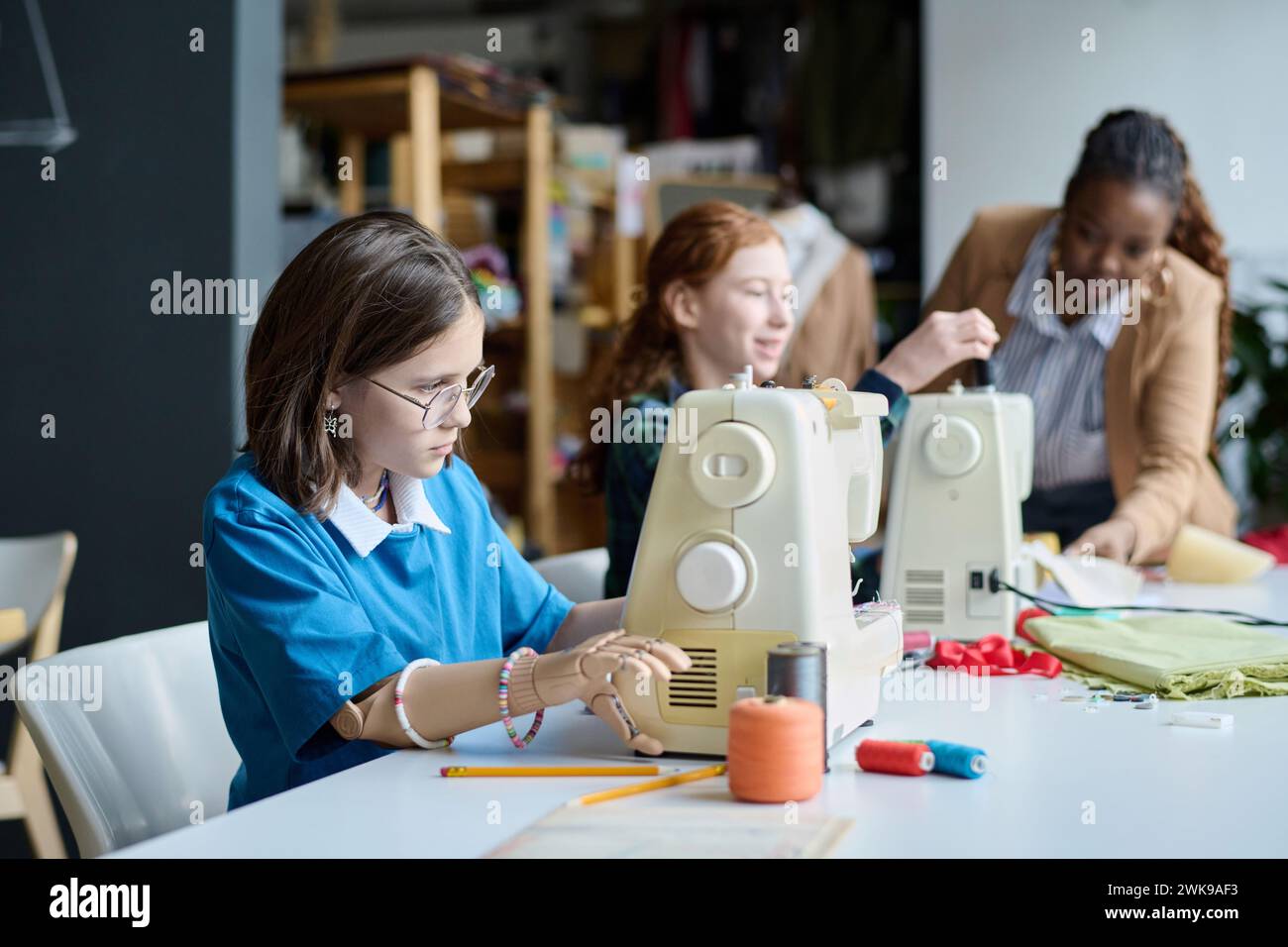 Vue latérale portrait de fille avec main prothétique à l'aide de la machine à coudre dans la classe de couture Banque D'Images