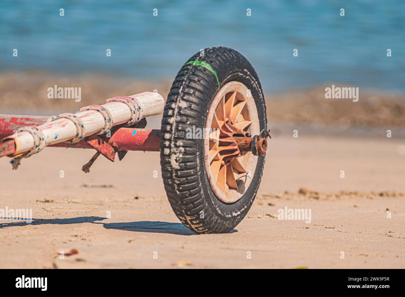 Roue de wagon debout sur une plage avec l'océan en arrière-plan sur une journée ensoleillée. Banque D'Images