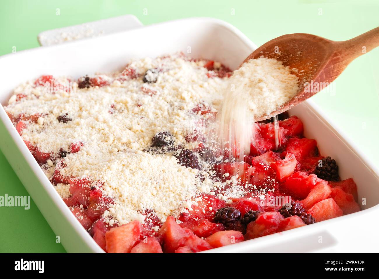 Un mélange de crumble est saupoudré sur la pomme ramollie et les mûres mijotées pour faire un crumble de mûre et de pomme. Un désert anglais traditionnel Banque D'Images