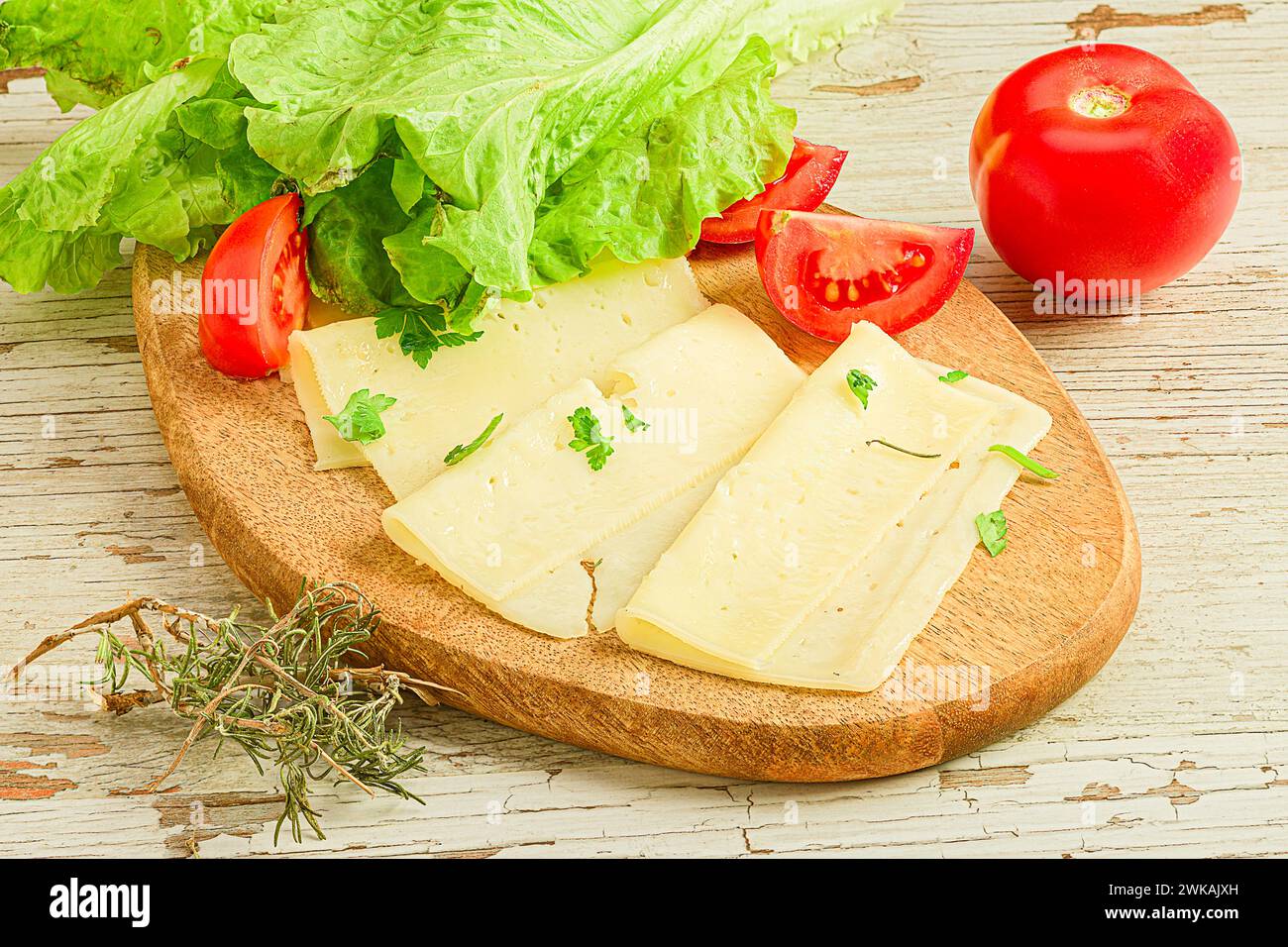 Tranches de fromage, tomates et laitue sur une planche à découper en bois Banque D'Images