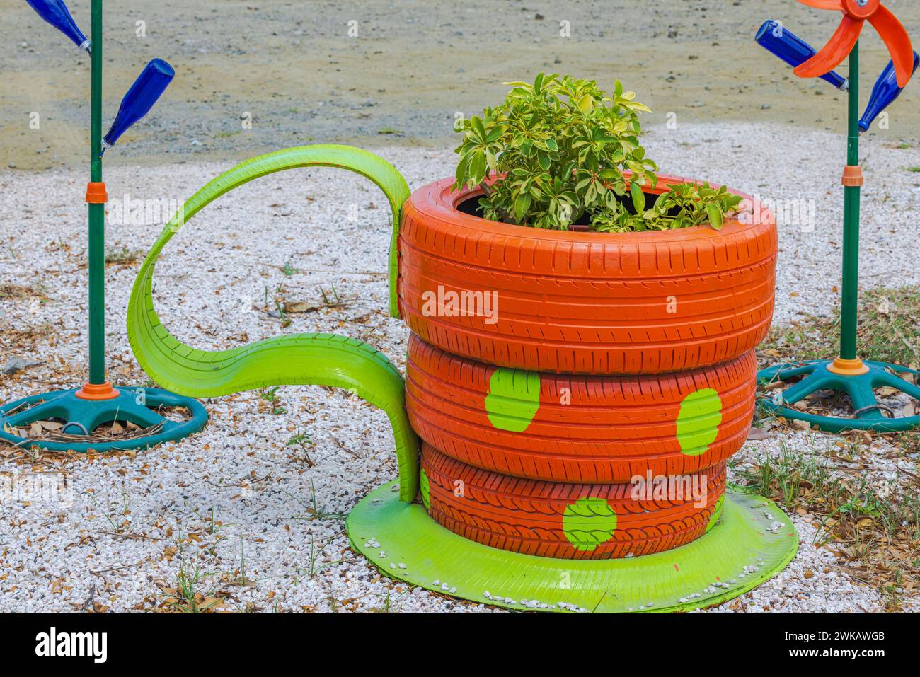 Vue sur un parterre de fleurs vibrant conçu comme une tasse à café, fabriqué à partir de vieux pneus de voiture inutilisables, remplis de plantes tropicales. Banque D'Images